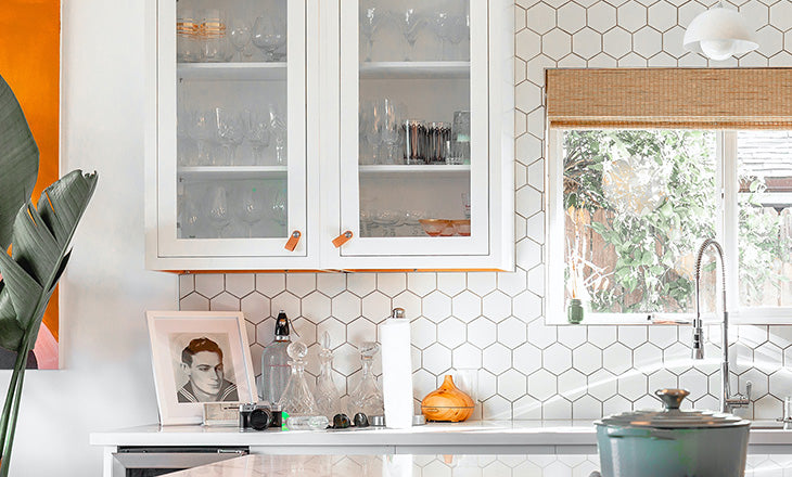 A close-up of the kitchen photo compressed with Photoshop at 1x scale, centering on a cabinet and background tiles, with various accessories on the counter. The grout lines show the pixelation.